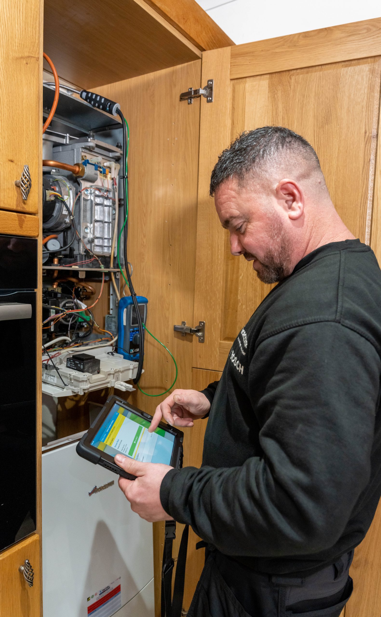 Jay completing a gas safety inspection record beside a boiler